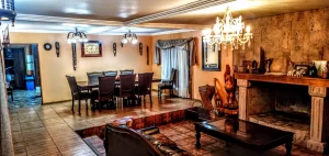 Amplio living comedor con chimenea de piedra, lámparas de candelabro y araña de cristal.