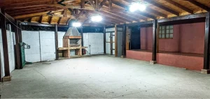 Estructura de quincho monumental de 96 m2 con vigas de roble a la vista y parrilla en obra.